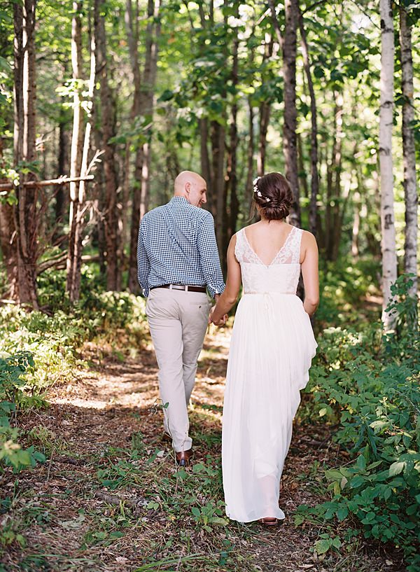bride and groom walking into the woods