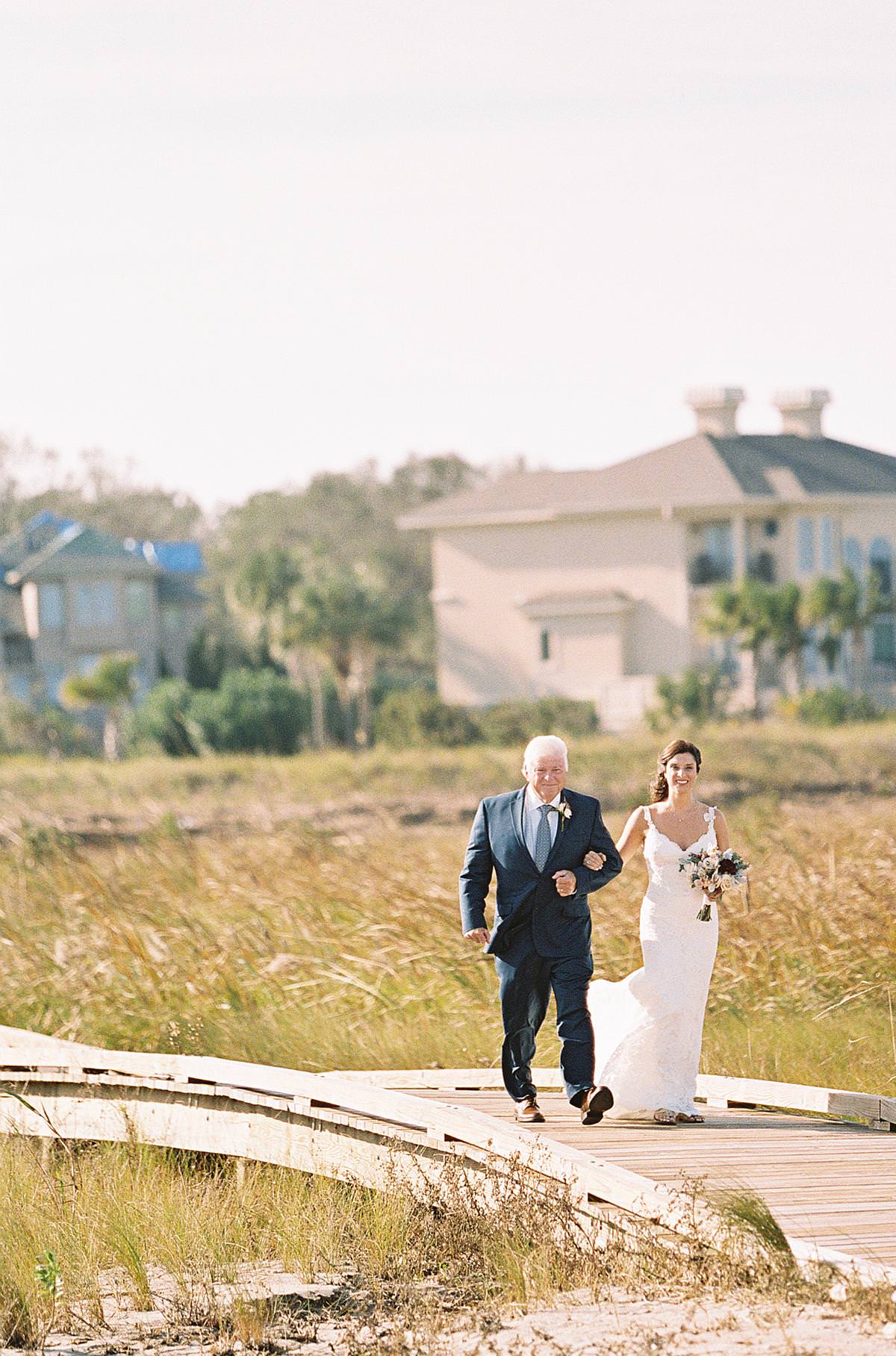 father walking bridal to beach ceremony